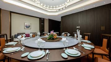 A round dining table set with plates, cutlery, and glasses, surrounded by chairs.