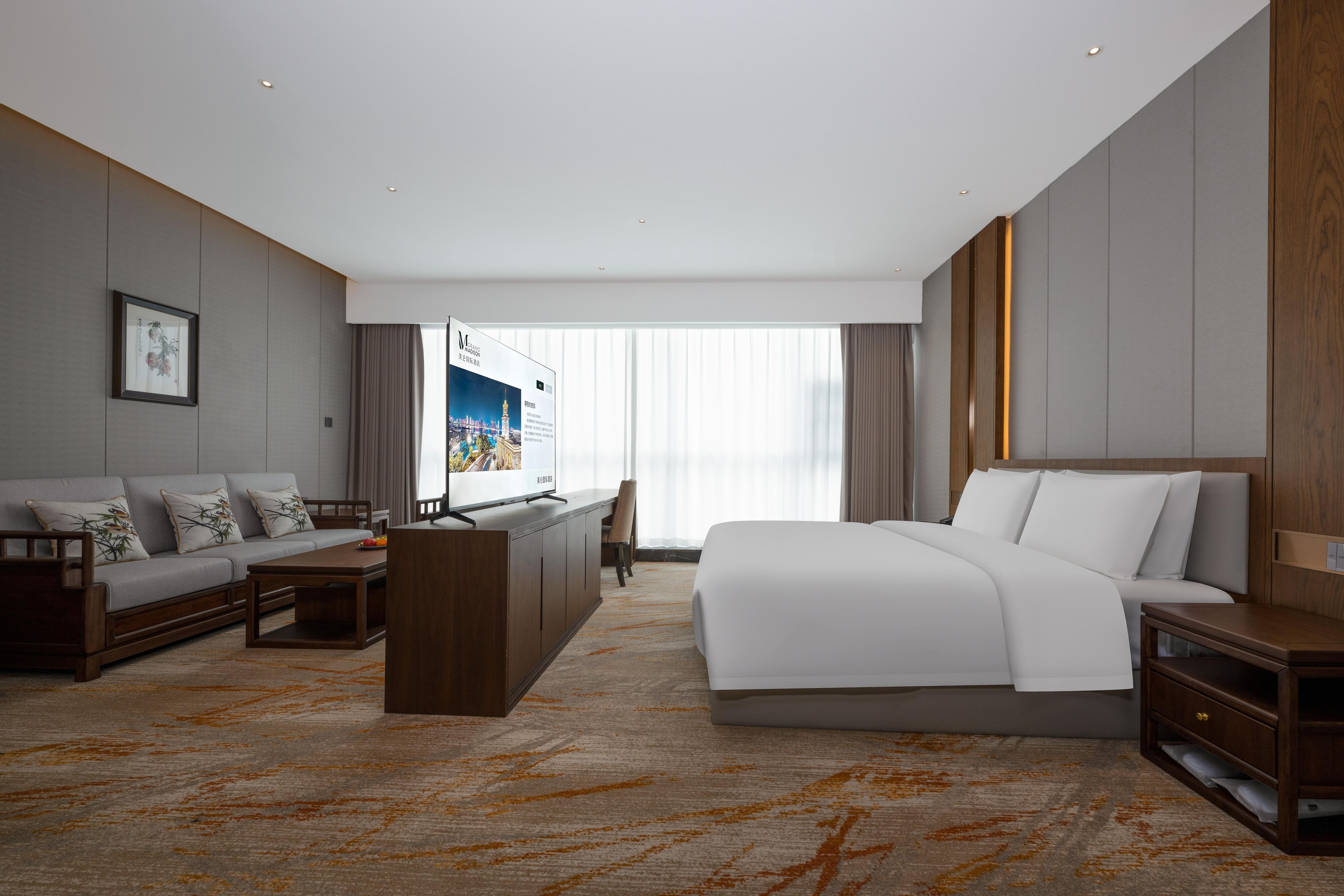 A hotel room with a bed, a sofa, a desk, and a large window.