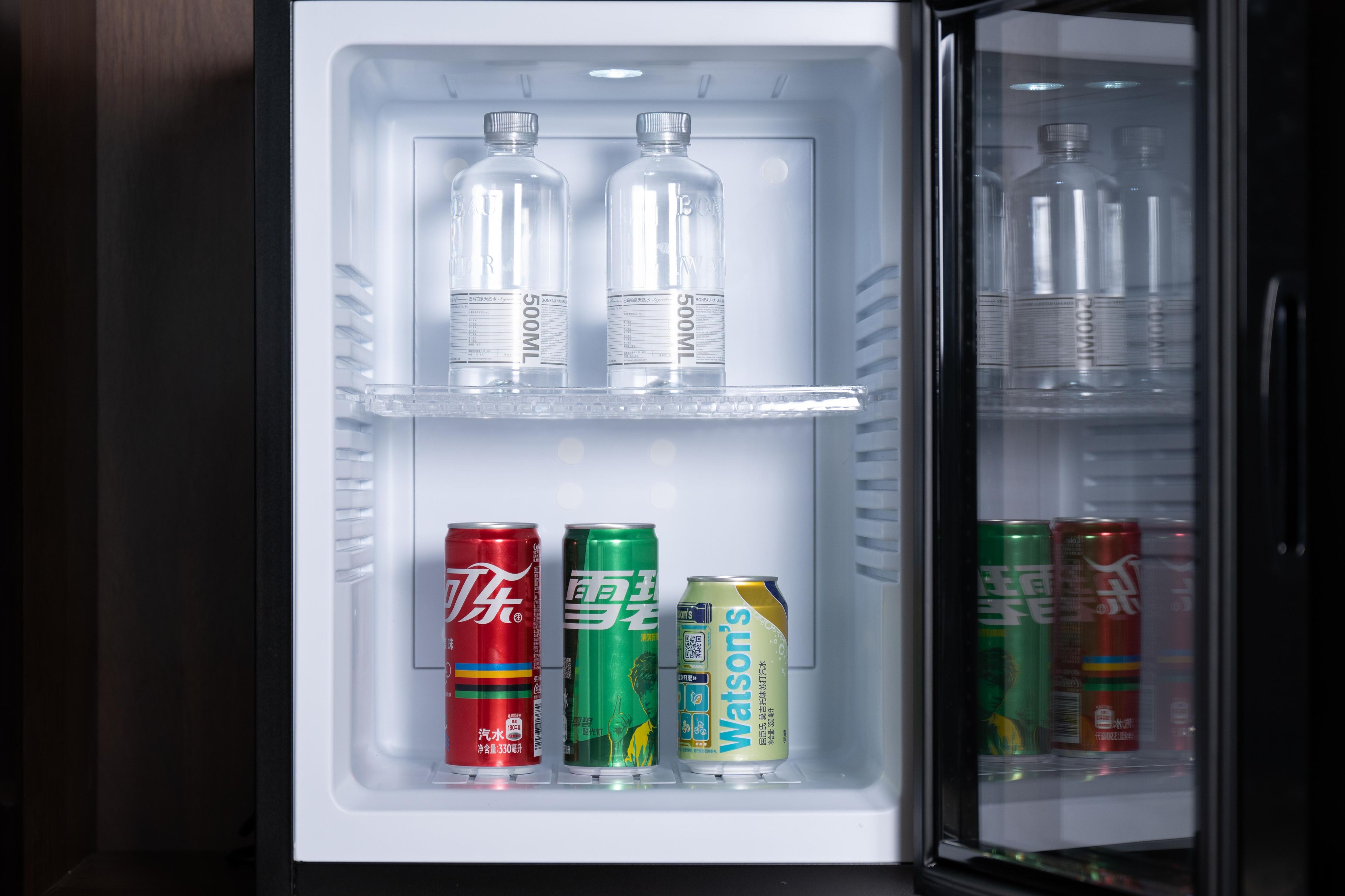 Een koelkast gevuld met flessen en blikjes drank.