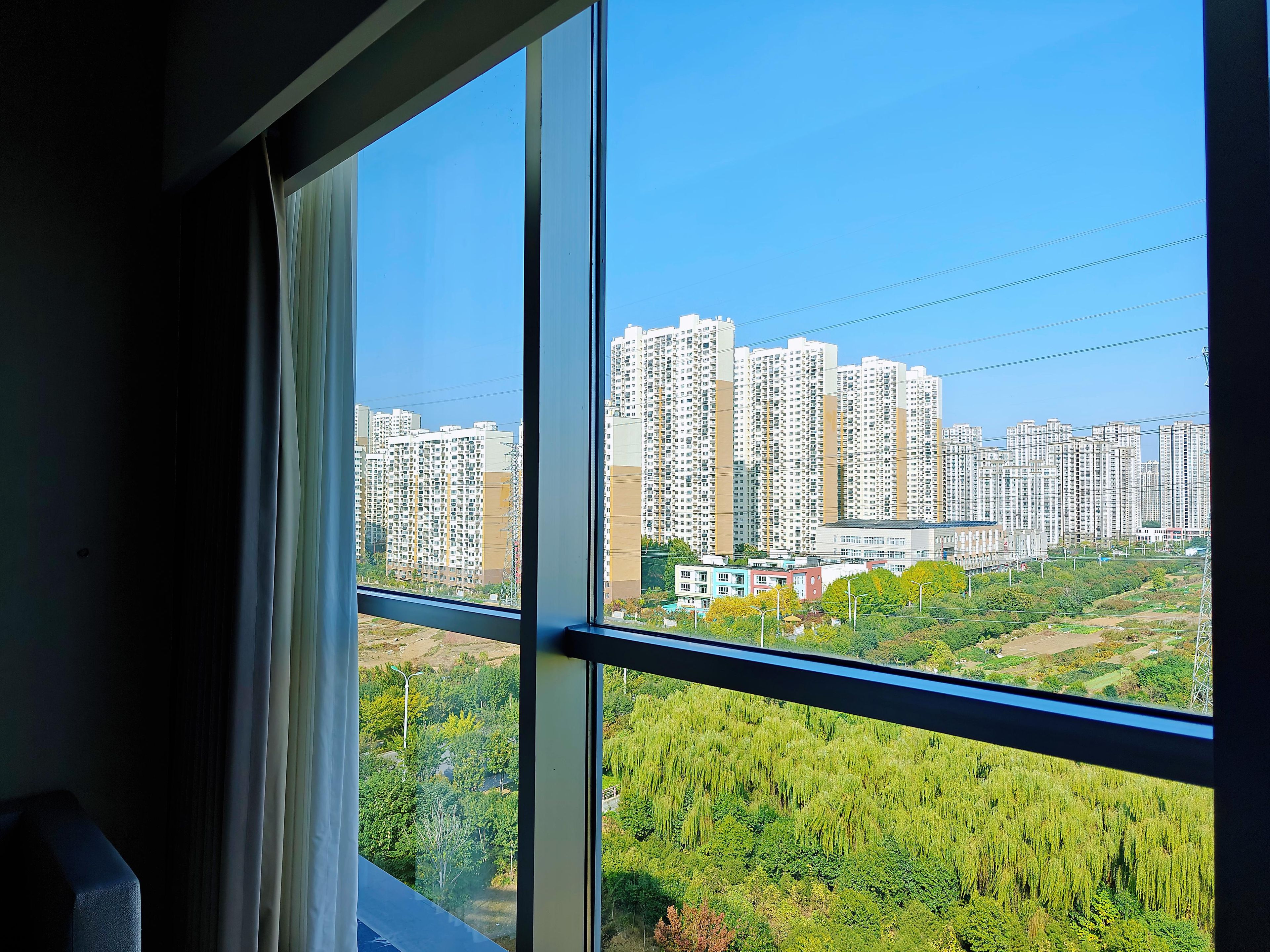 A view from a window overlooking a cityscape with high-rise buildings and greenery.