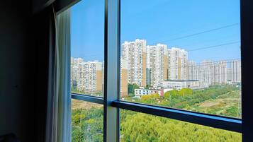 A view from a window overlooking a cityscape with high-rise buildings and greenery.