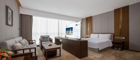 A hotel room with a bed, a desk, a sofa, and a coffee table.