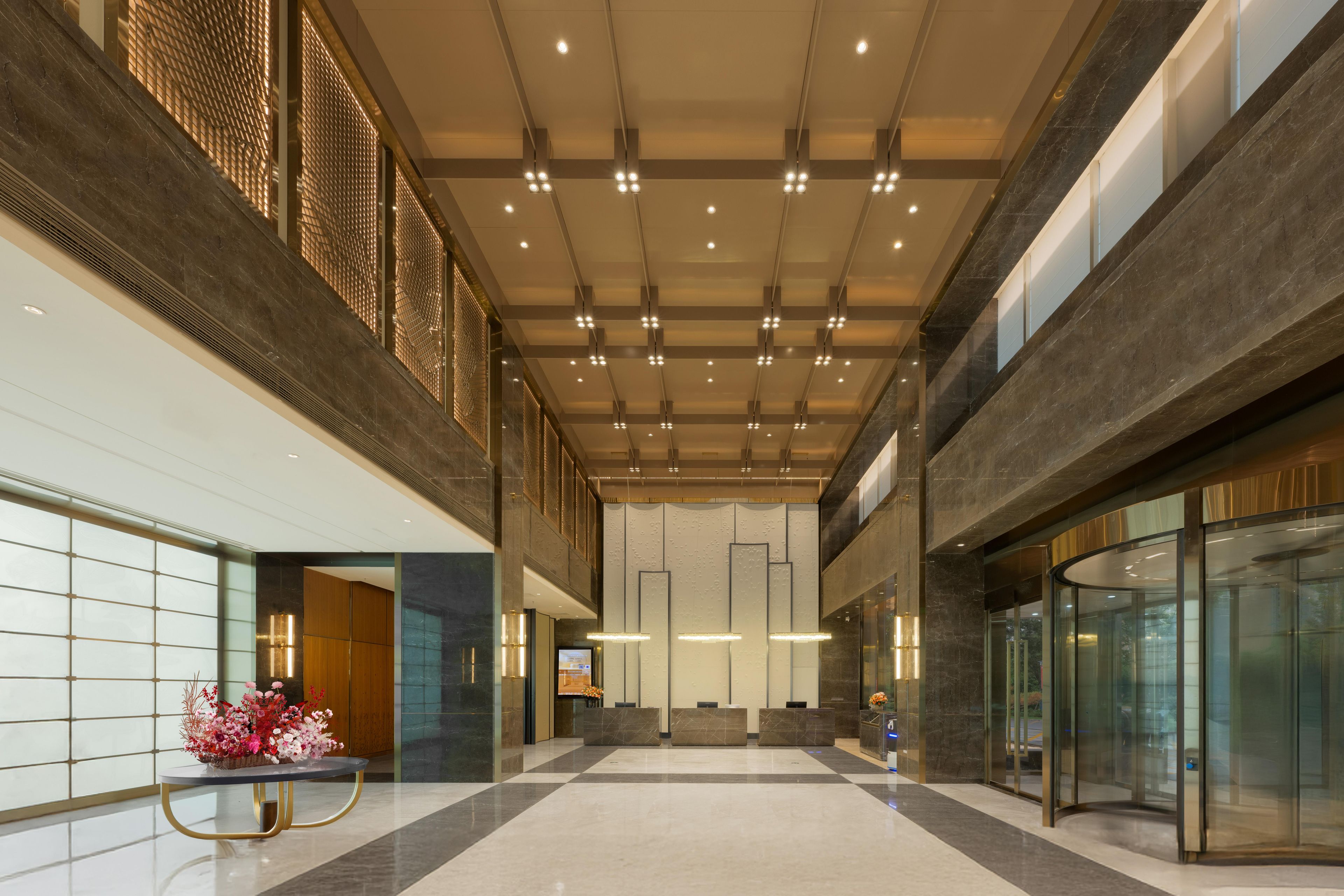 A spacious lobby with a high ceiling, modern lighting, and a reception desk.