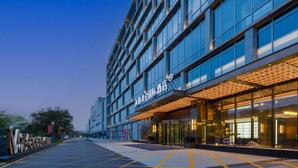 A modern hotel with a glass facade, a prominent entrance, and a well-lit exterior. - Grand Madison Hotel Jining Yongrun (Jining)