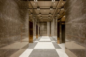 A modern elevator interior with marble walls and a checkered floor pattern. - Grand Madison Hotel Jining Yongrun (Jining)
