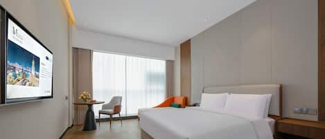 A modern hotel room with a large bed, a desk with a chair, a TV on the wall, and a large window with curtains.