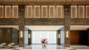 A spacious lobby with a high ceiling, a central floral arrangement, and a seating area with two chairs. - Grand Madison Hotel Jining Yongrun (Jining)