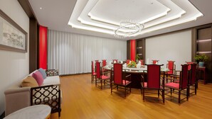 A dining area with a round table, red chairs, and a chandelier.