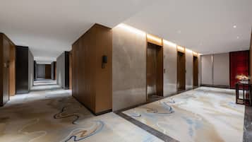 Un pasillo largo en un hotel, con puertas de madera y una alfombra estampada.