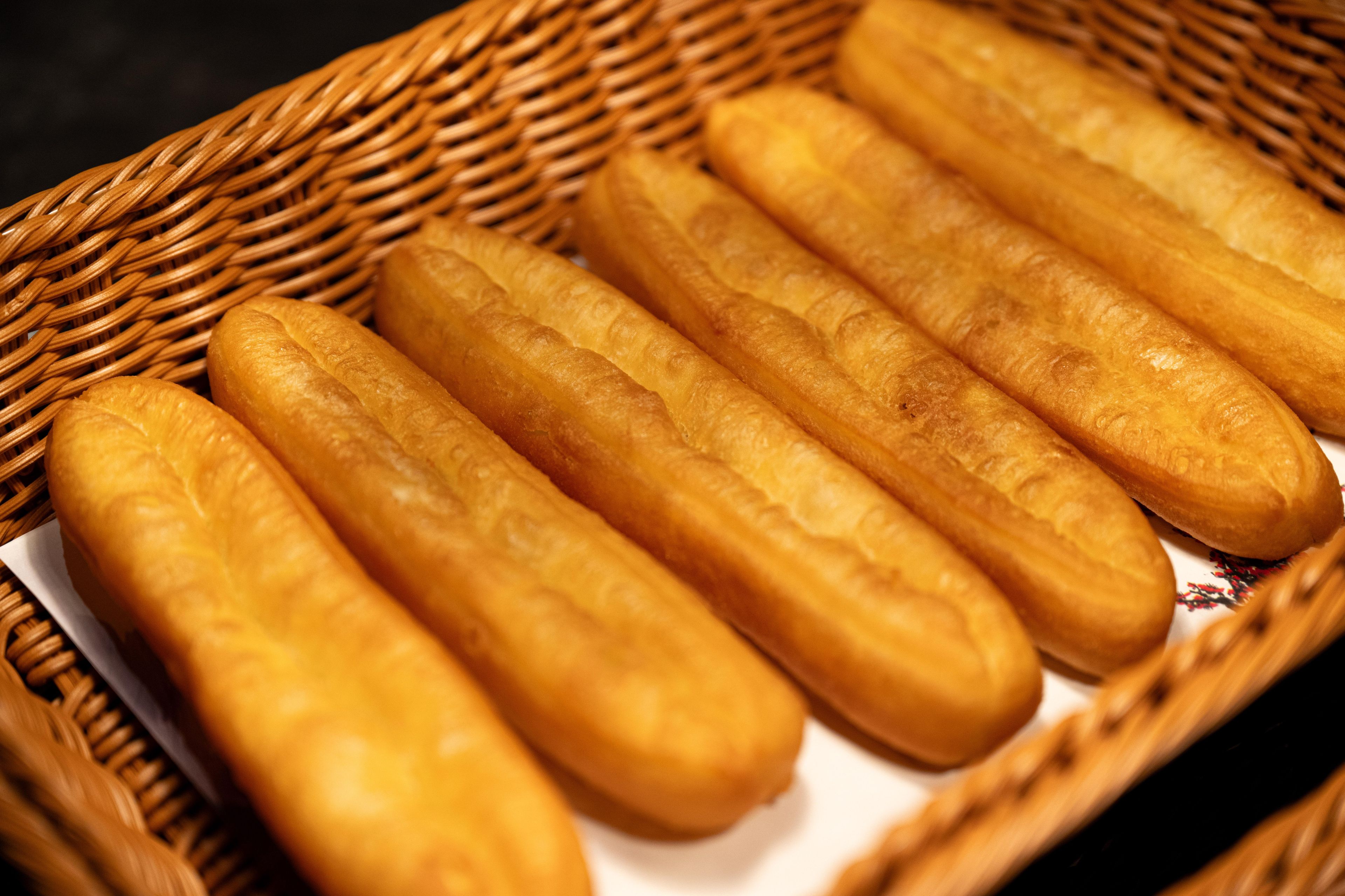 A basket containing several long, golden-brown breadsticks.