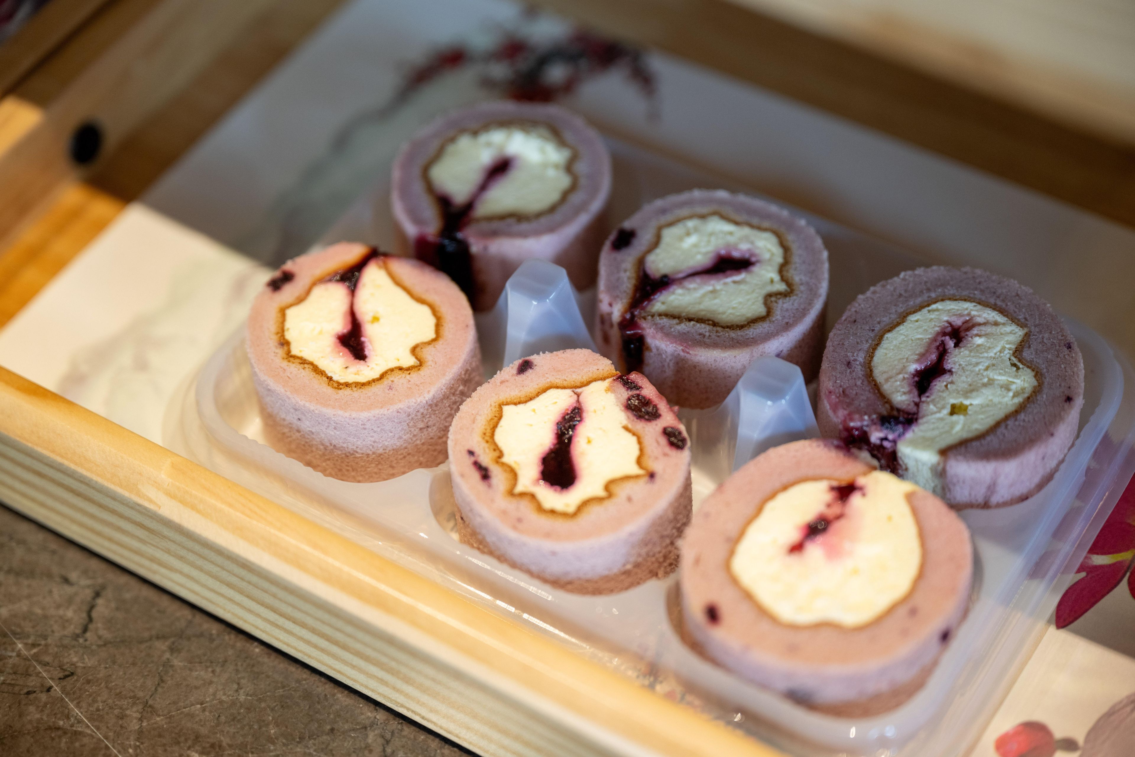 A tray of rolled desserts with a creamy filling and berry compote.