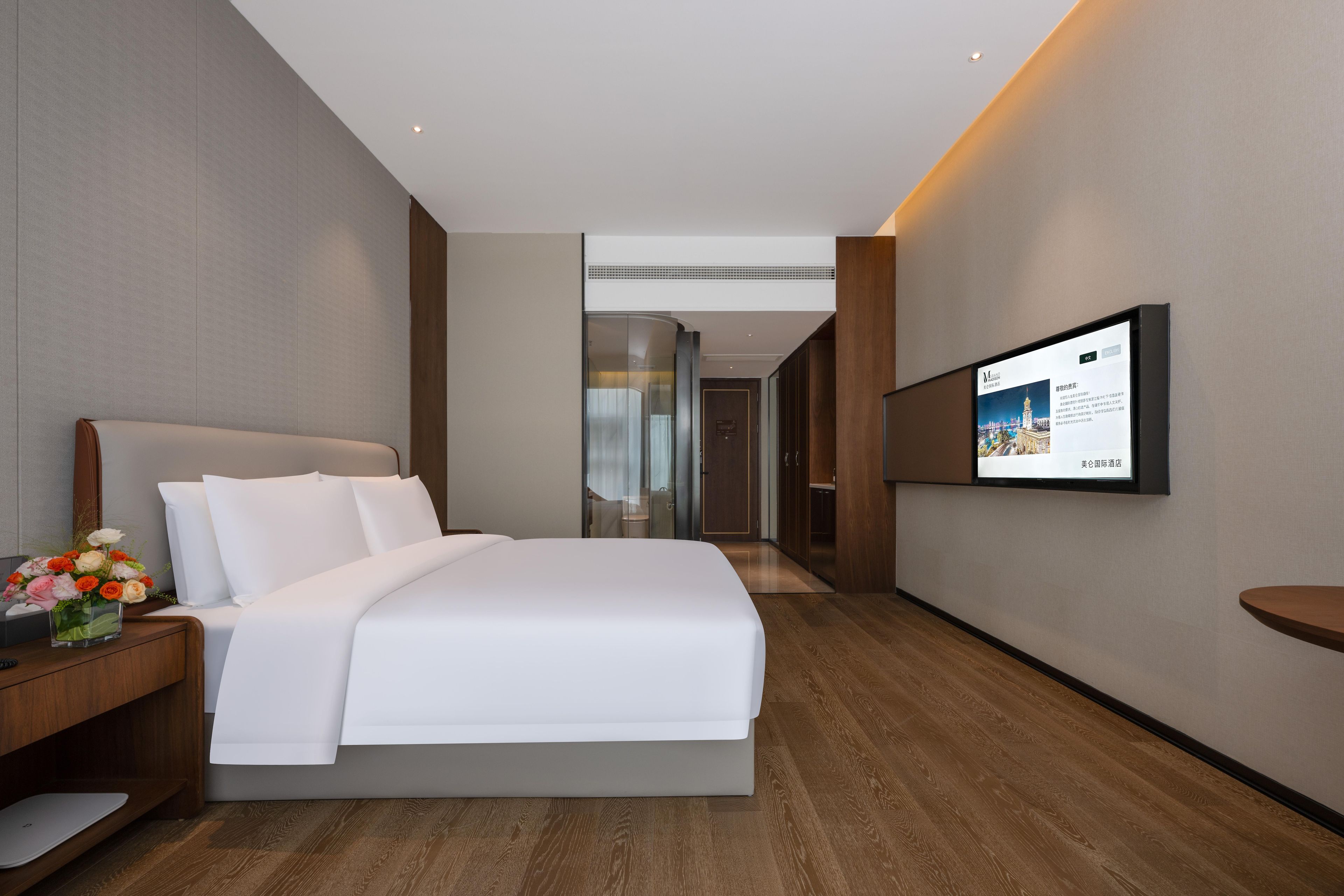 Habitación de hotel con una cama grande, un televisor de pantalla plana montado en la pared y suelo de madera.