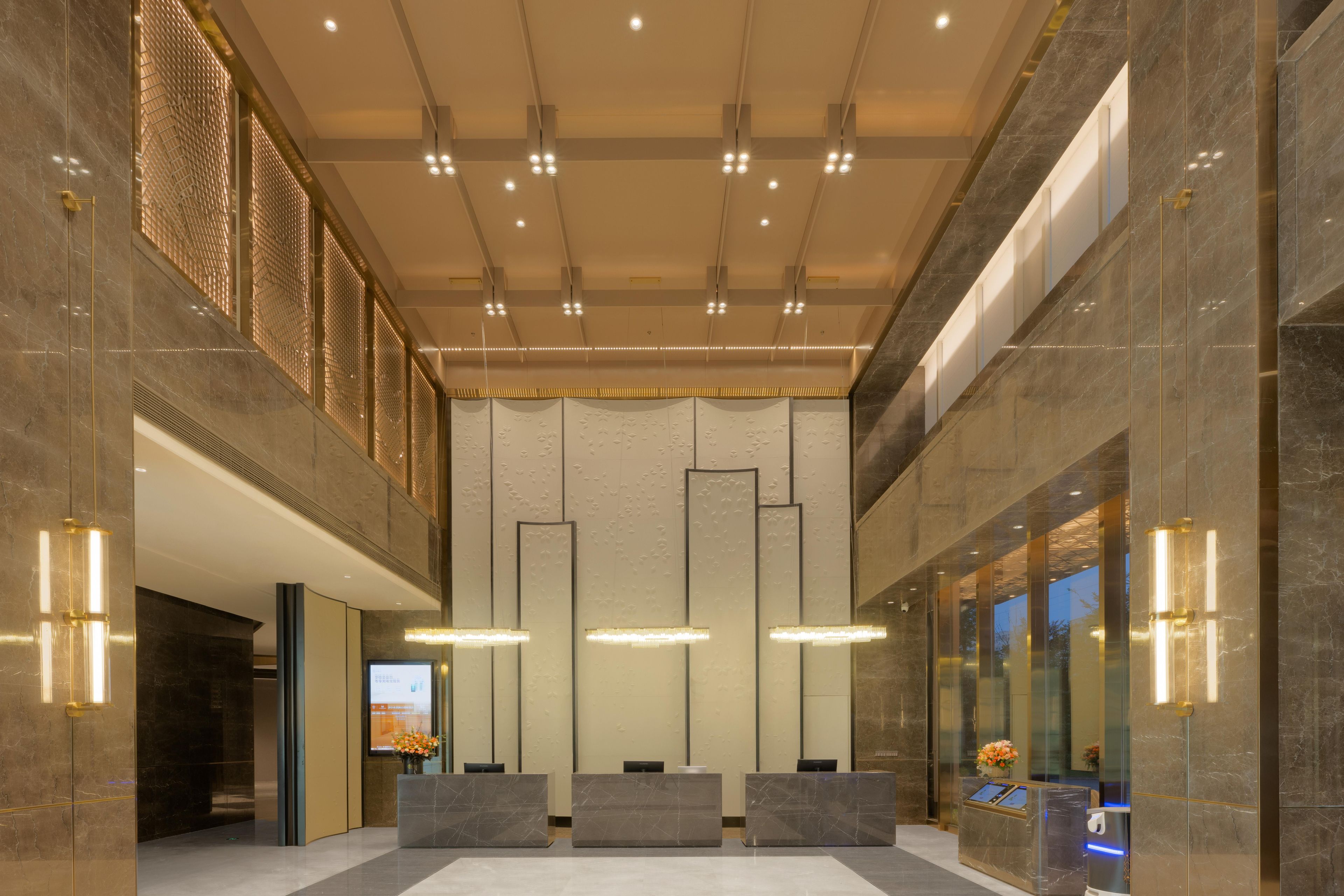 A modern lobby with marble floors, a reception desk, and a digital display.