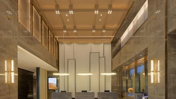 A modern lobby with marble floors, a reception desk, and a digital display.