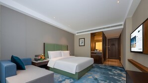 Habitación de hotel con cama, escritorio, silla, televisión y puerta que da a un baño.