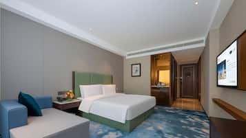 Habitación de hotel con cama, escritorio, silla, televisión y puerta que da a un baño.