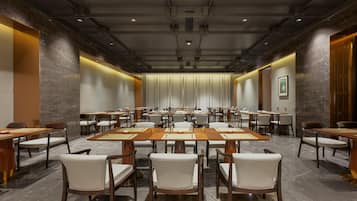A conference room with multiple tables and chairs, equipped with nameplates and a projector.