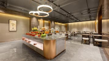 A modern hotel lobby with a central bar area, seating arrangements, and a polished marble floor.