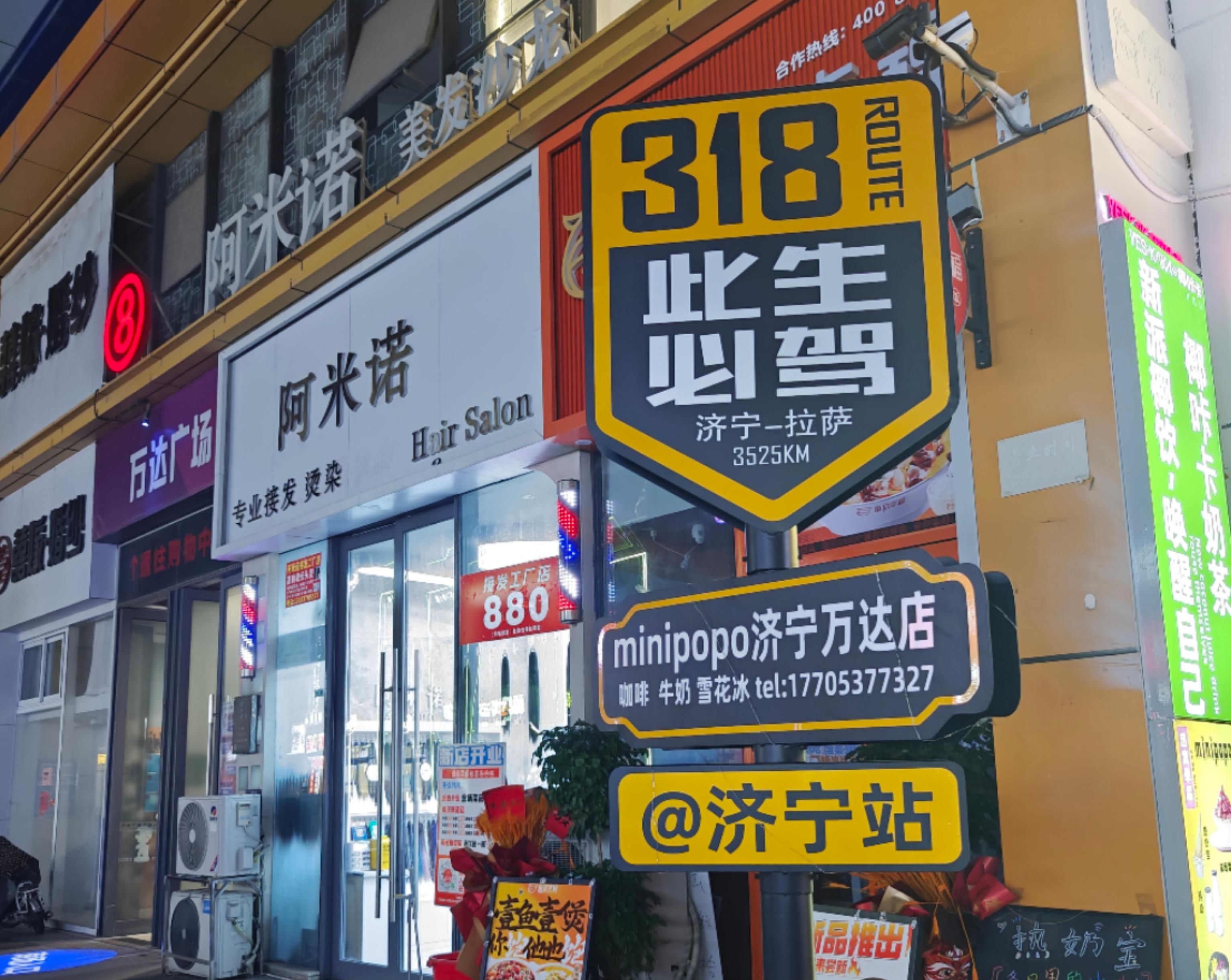 Une vue d’une rue avec différents panneaux, dont un grand panneau jaune portant le numéro 318 et, au-dessus, un panneau indiquant un salon de coiffure.