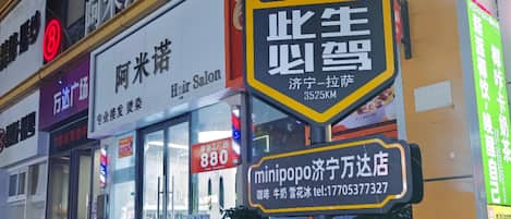 A street view with various signs, including a prominent yellow sign with the number 318 and a hair salon sign above it.