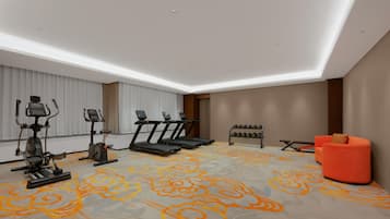 Une chambre d’hôtel moderne dotée d’un espace de remise en forme comprenant des tapis de course, un appareil elliptique et un ensemble d’haltères.