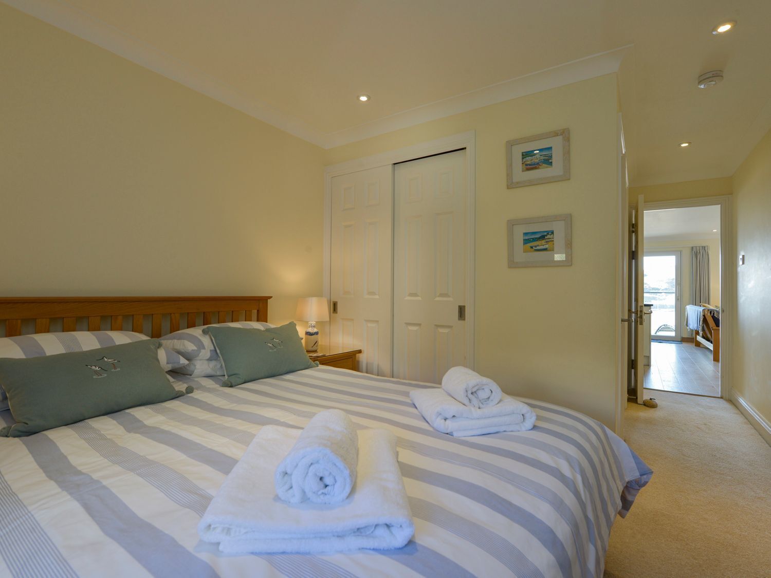 Habitación de hotel con cama, almohadas, mesita de noche y una puerta.