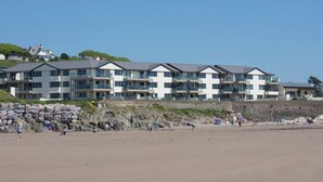 A coastal hotel with multiple balconies, a sandy beach in the foreground, and a rocky cliff in the background. - 12 Burgh Island Causeway (Kingsbridge)