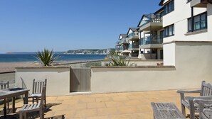 A beachfront property with a patio area featuring wooden furniture and a view of the sea. - 12 Burgh Island Causeway (Kingsbridge)