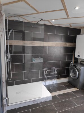 A modern bathroom with a glass-enclosed shower, a white sink, and a washing machine.