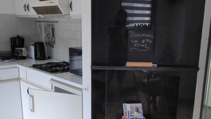 Een moderne keuken met witte kasten, een zwarte koelkast en een klein houten plankje met een zacht speeltje.