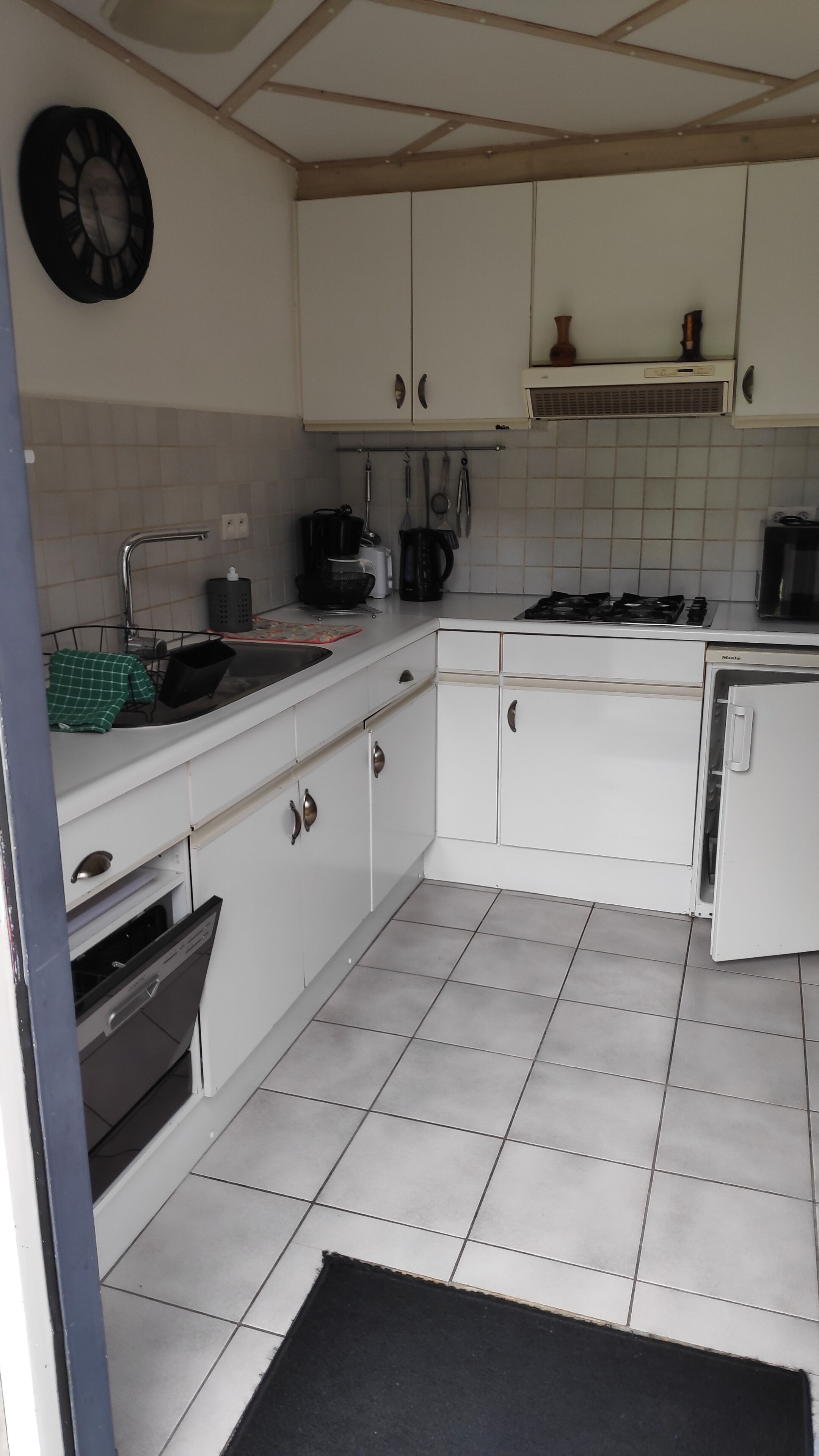 A kitchen with white cabinets, a stove, a sink, and a clock on the wall.
