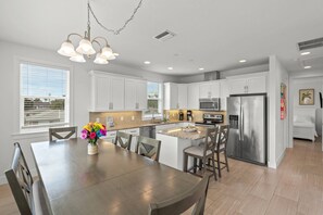 Una cocina moderna con armarios blancos, electrodomésticos de acero inoxidable y una isla central con asientos.