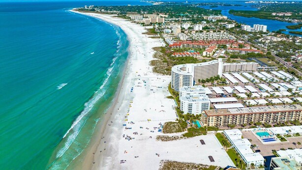 An aerial view of a coastal city with a long sandy beach, a marina, and a mix of residential and commercial buildings. - Lido Dream Combined Duplex Both N & S (Sarasota)