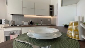 A modern kitchen with white cabinets, a gas stove, a microwave, and a sink. - Tranquility and comfort near Careggi, 10 min from center by tramway (Firenze)