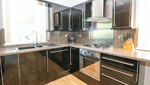 A modern kitchen with black cabinets, stainless steel appliances, and a wooden floor. - Flat 2, Omega Court (Whitehaven)