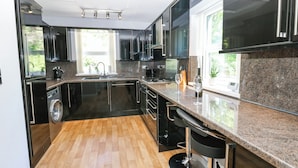 A modern kitchen with black cabinets, a stainless steel sink, and a granite countertop. - Flat 2, Omega Court (Whitehaven)