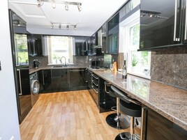 Een moderne keuken met zwarte kastjes, een roestvrijstalen spoelbak en een granieten werkblad.