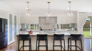 Una cocina moderna con una isla central, taburetes de bar e iluminación colgante.