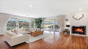 A modern living room with a white sofa, a coffee table, and a fireplace.