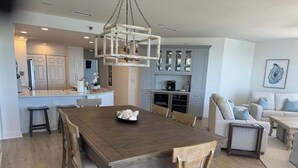 Un vaste espace de vie comprenant une grande table à manger en bois, une cuisine équipée d’appareils modernes et un coin salon confortable avec un canapé et des fauteuils.