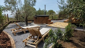 A patio area with wooden lounge chairs, a hot tub, and a wooden deck. - Koru (Belpasso)