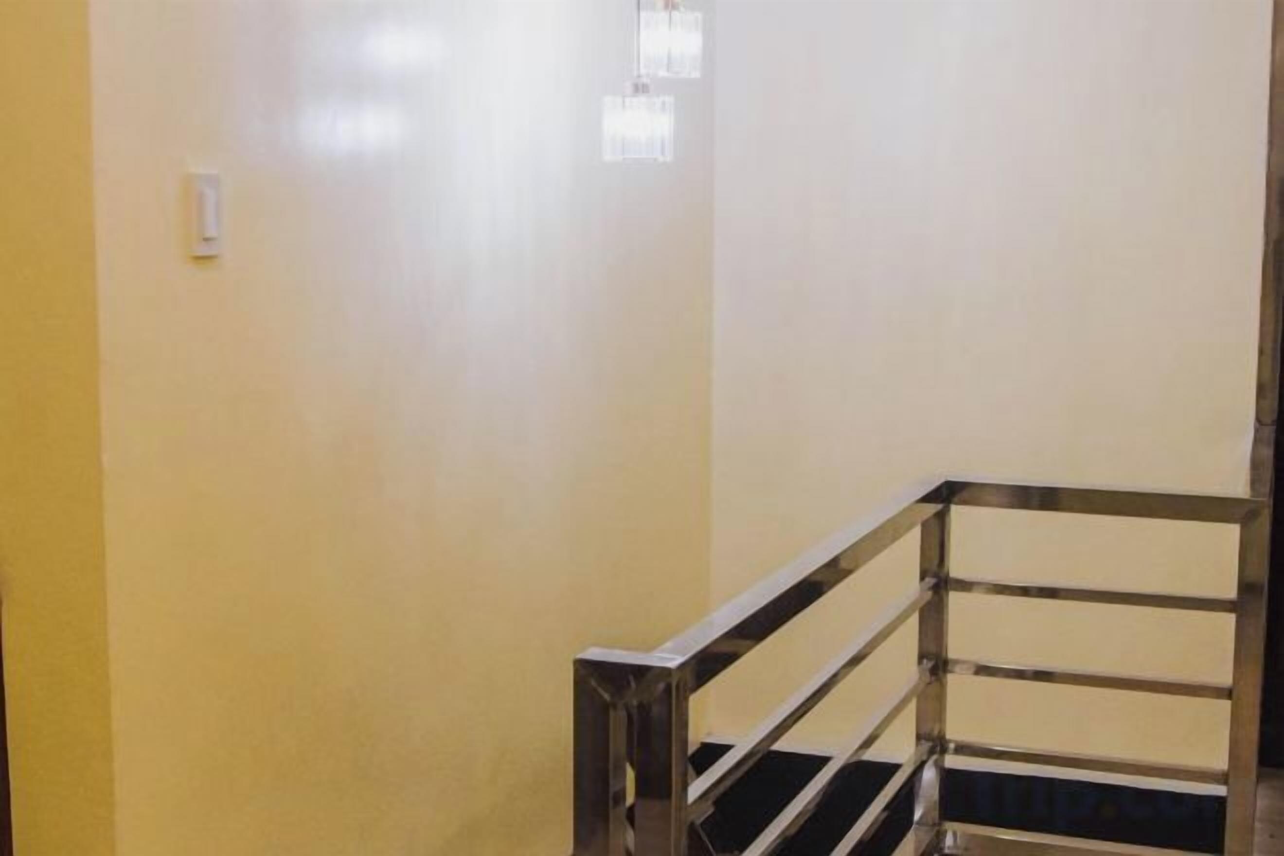 Una escalera con barandilla metálica y un interruptor de luz en la pared.