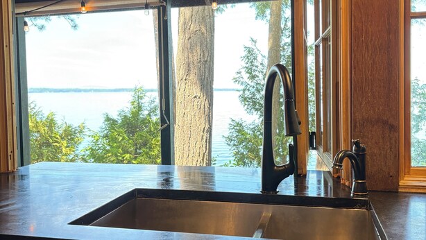 A kitchen with a large window, a sink, and pendant lighting.