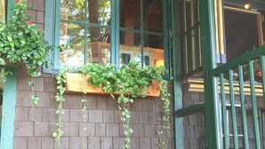 A brick building with green-framed windows and a wooden bench outside.