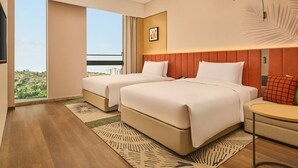 A hotel room with two beds, a small table, a chair, a large window with a view, and a ceiling light fixture. - Hilton Garden Inn Chongqing Yubei Central Park (Chongqing)