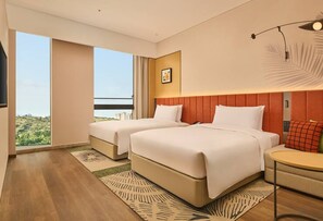 A hotel room with two beds, a small table, a chair, a large window with a view, and a ceiling light fixture. - Hilton Garden Inn Chongqing Yubei Central Park (Chongqing)