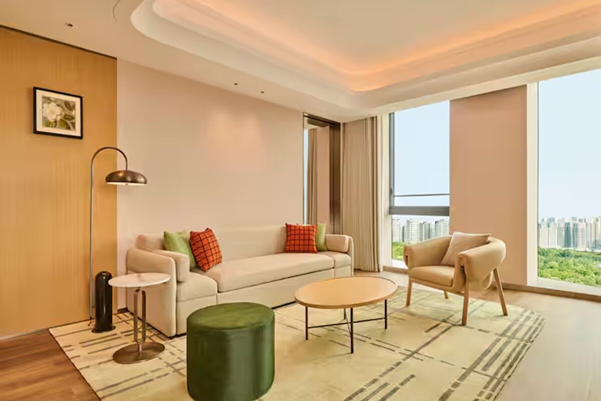 A modern living room with a sofa, armchair, coffee table, and floor lamp.