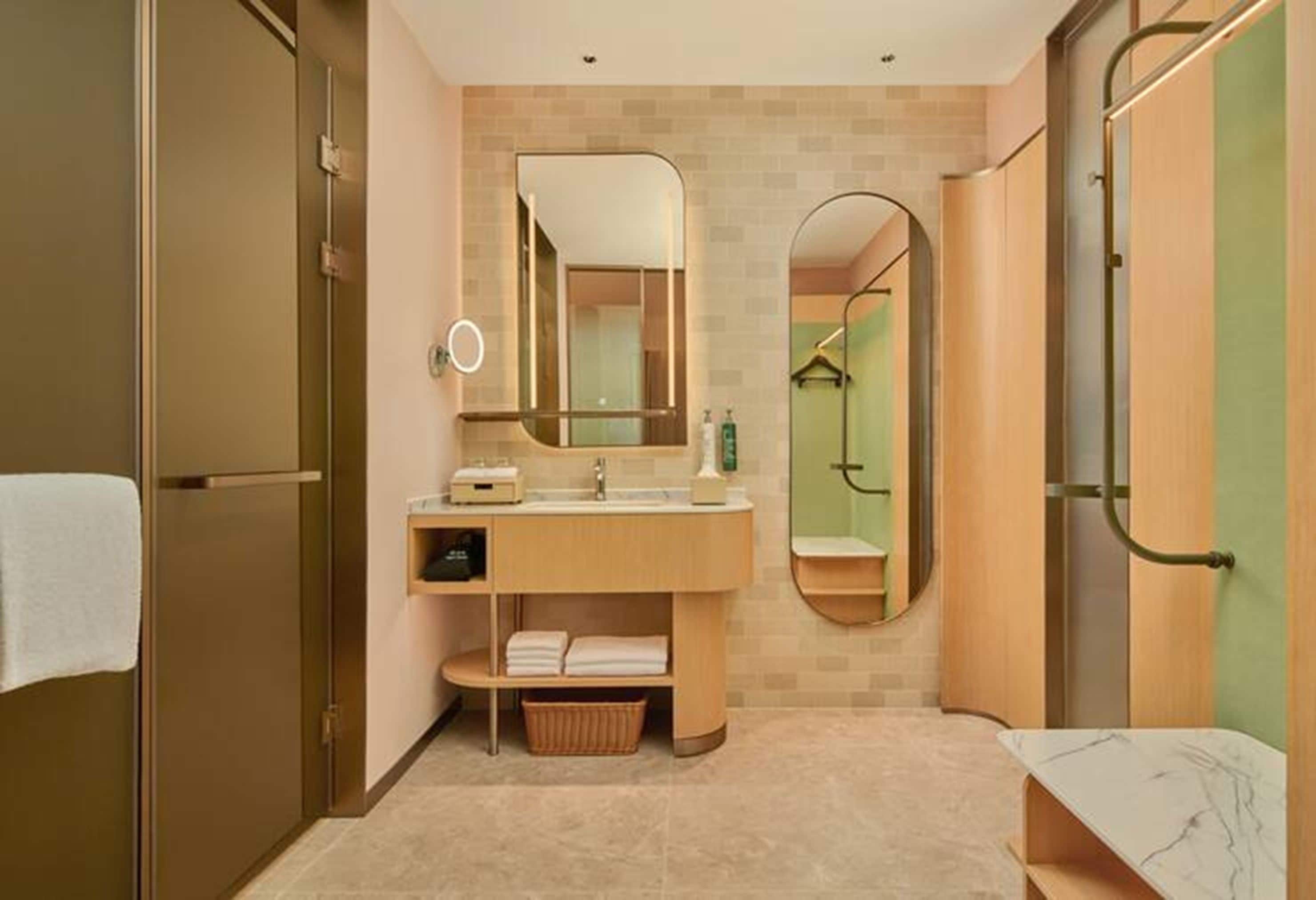 A modern bathroom with a wooden vanity, a large mirror, and a towel rack.