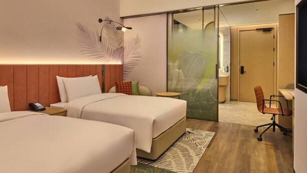 A hotel room with two beds, a desk, a chair, and a large mirror. - Hilton Garden Inn Chongqing Yubei Central Park (Chongqing)