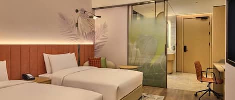 A hotel room with two beds, a desk, a chair, and a large mirror.